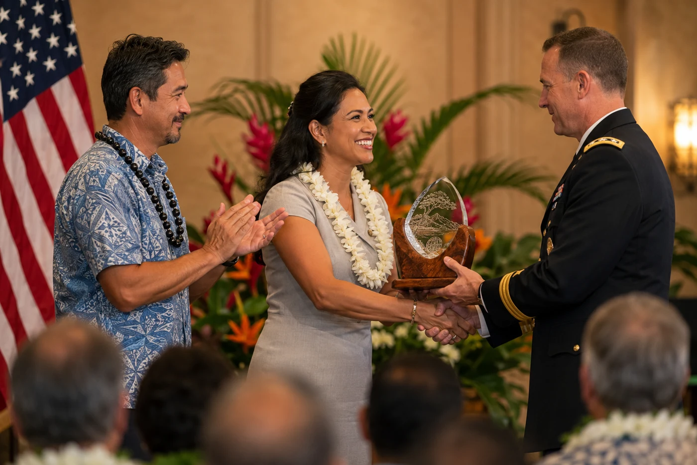 An environmental professional in a plumeria lei receives an engraved award from a U.S. Army officer at a formal federal ceremony — national recognition for Pacific environmental innovation.